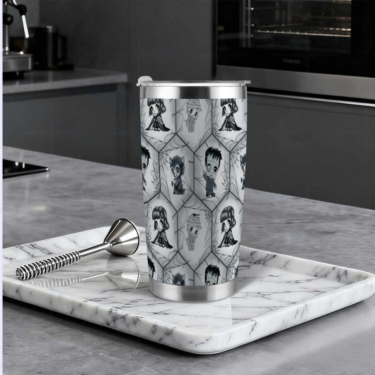 Grayscale monster tumbler on a marble tray in a modern dark kitchen beside a cocktail muddler