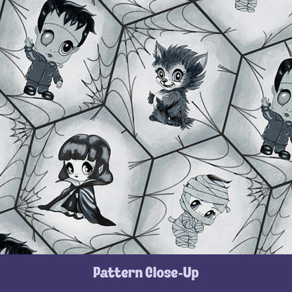Close-up of the black and white monster pattern showing hand-drawn chibi Frankenstein, werewolf, vampire, and mummy inside interlocking hexagon blocks filled with fine-line spiderwebs