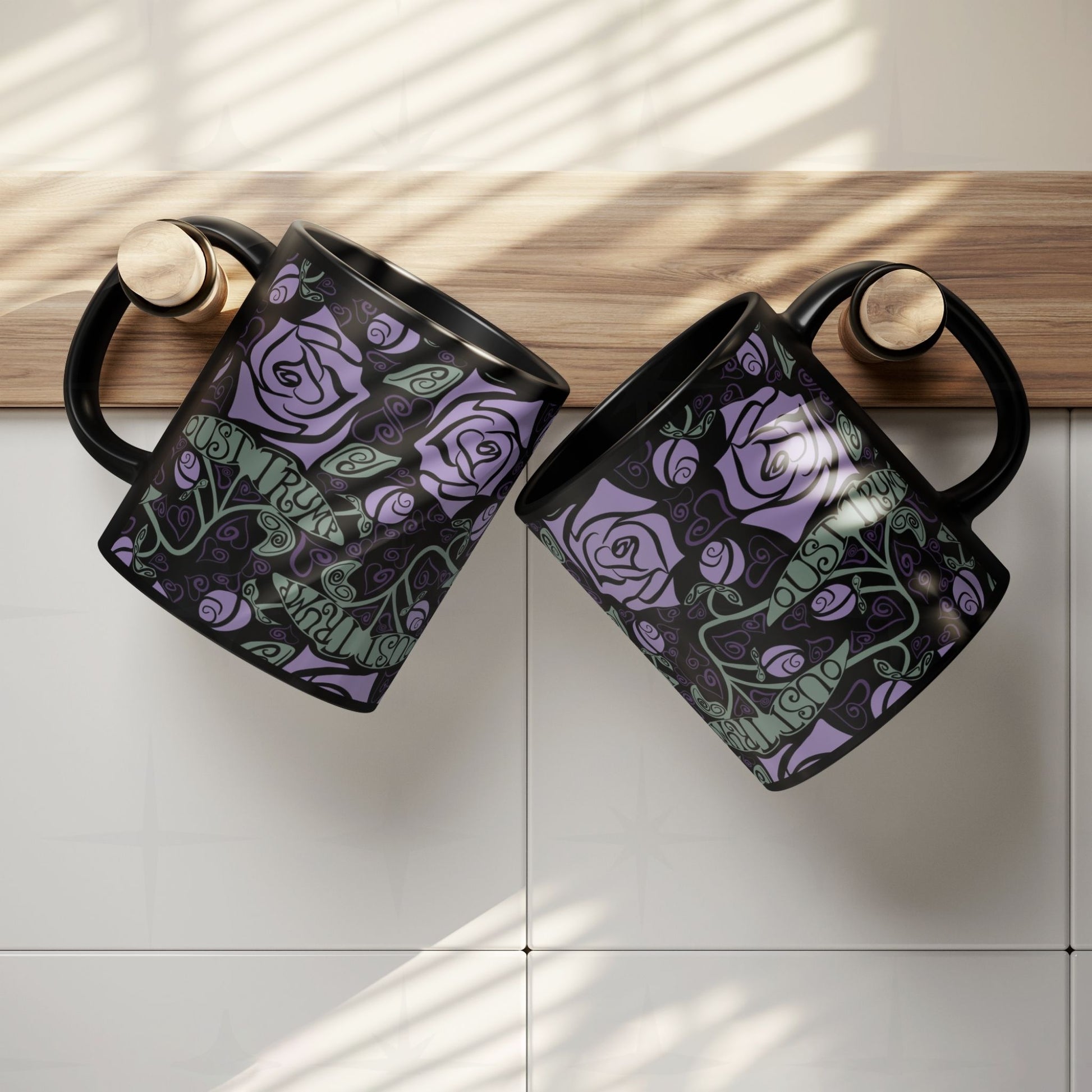 Two anti-Trump hidden message mugs with gothic rose botanical print hanging on kitchen cabinet edge