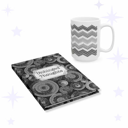 White ceramic mug with five gray chevron stripes beside a black hardcover journal covered in white concentric circles with an Unhinged Thoughts label plaque.