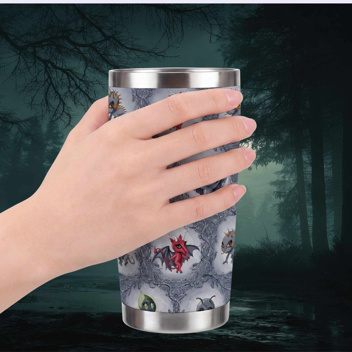 Hand holding the cryptid tumbler against a misty dark forest, with the crimson Jersey Devil facing forward