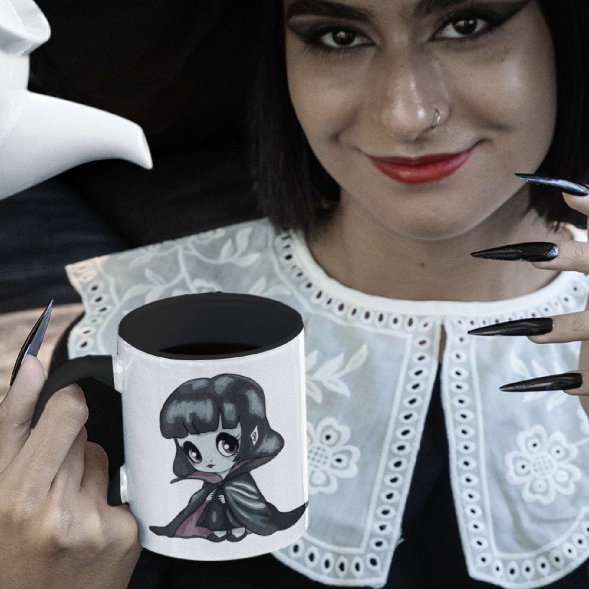 Woman with red lips and black nails holding the cute vampire coffee mug filled with black coffee