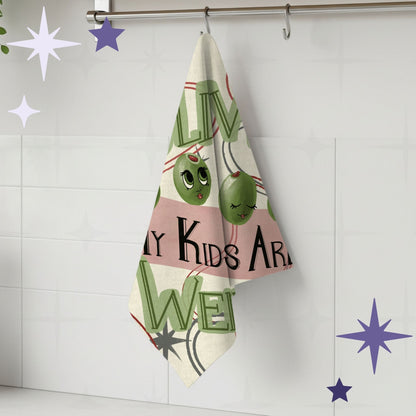 Funny retro tea towel hanging on kitchen rail showing olive pun design with cartoon olive faces and mid-century typography, cotton twill construction