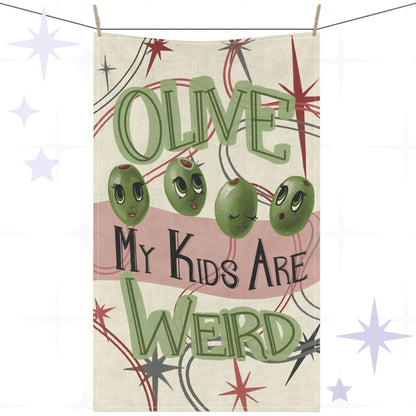 Funny olive pun tea towel with retro mid-century illustration reading "Olive My Kids Are Weird," featuring four cartoon olives with feminine faces, sage green hand-lettered typography, and atomic starburst motifs on cream cotton twill