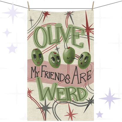Funny tea towel with retro mid-century olive illustration and hand-lettered pun reading "Olive my friends are weird," hung on a clothesline against a white background