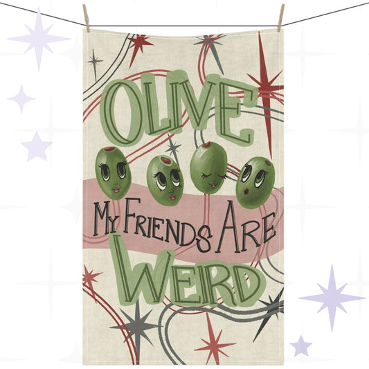 Funny tea towel with retro mid-century olive illustration and hand-lettered pun reading "Olive my friends are weird," hung on a clothesline against a white background