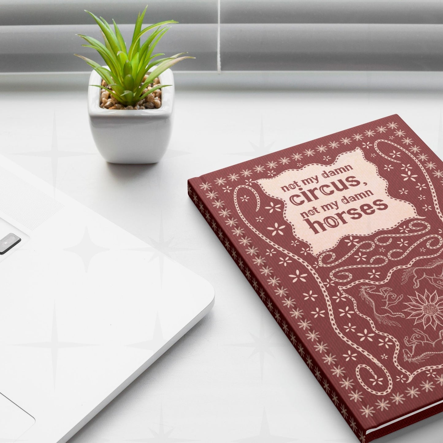 Snarky western journal on white desk next to laptop and small succulent plant showing not my damn circus hand-lettered cover