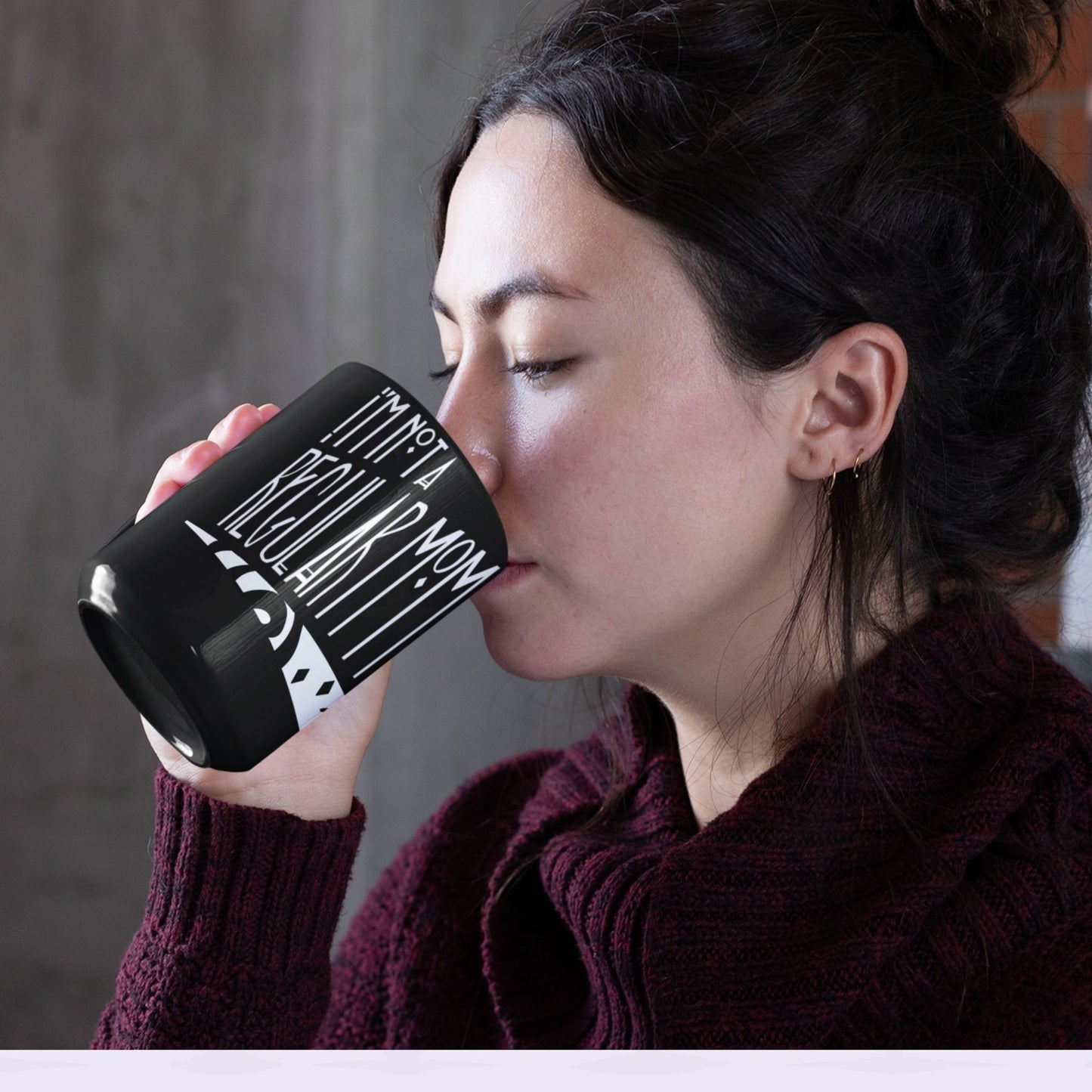 Woman with dark hair drinking from black goth mom mug showing I'm Not a Regular Mom gothic lettering, 11oz ceramic coffee cup