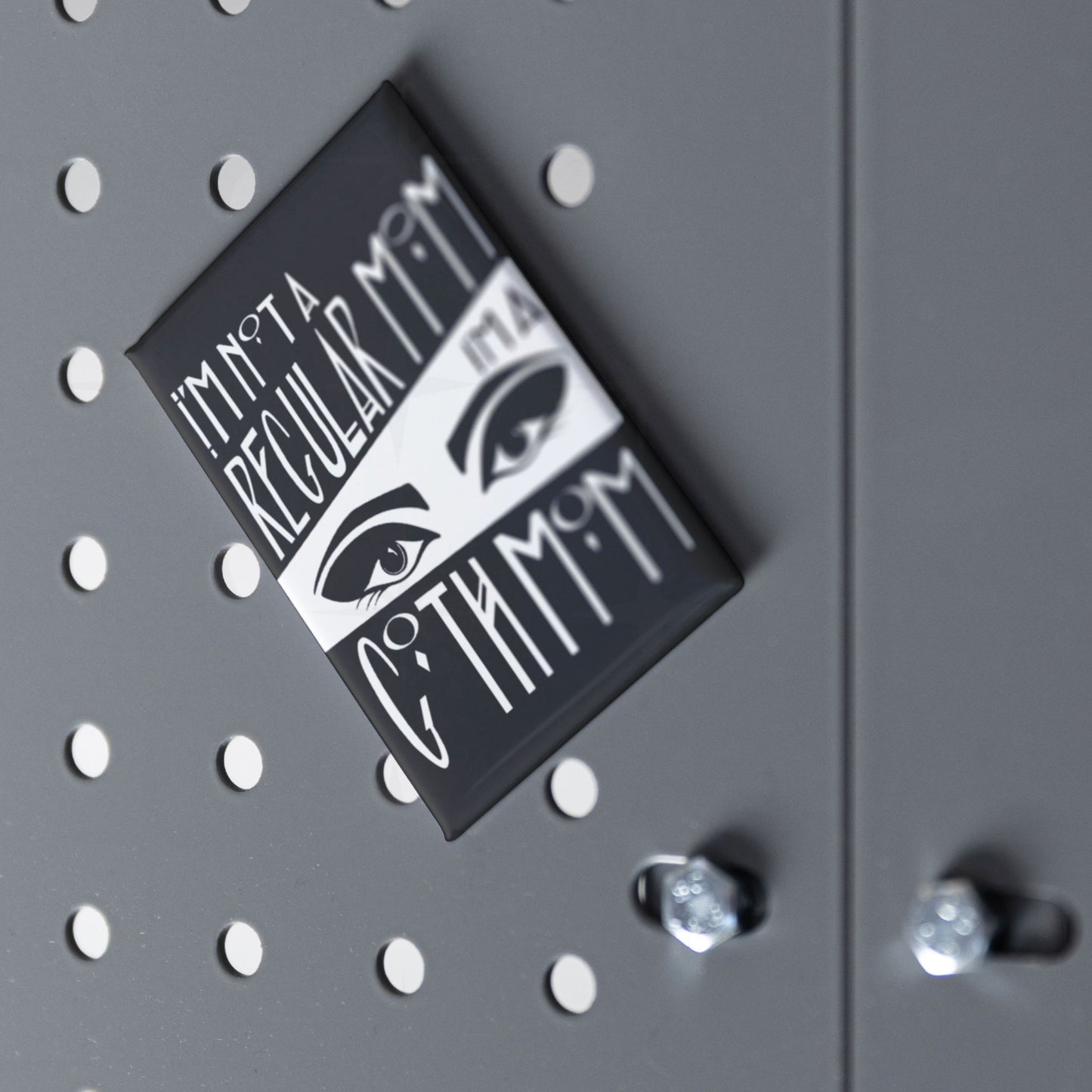 Goth mom fridge magnet displayed at an angle on a grey pegboard surface with chrome hardware visible