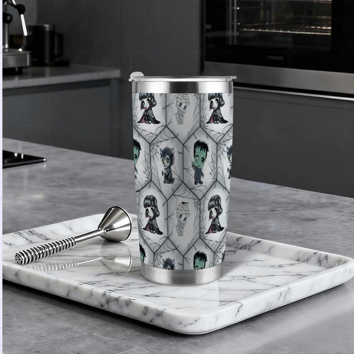 Chibi monster goth tumbler on a marble tray in a modern dark kitchen beside a cocktail muddler