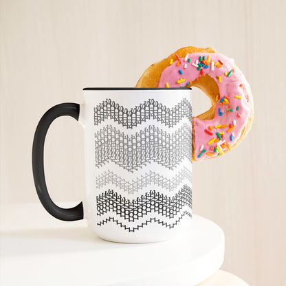 Gray & Black hidden message mug 15oz on white pedestal with a pink frosted sprinkle donut leaning against it — lifestyle product shot on warm cream background
