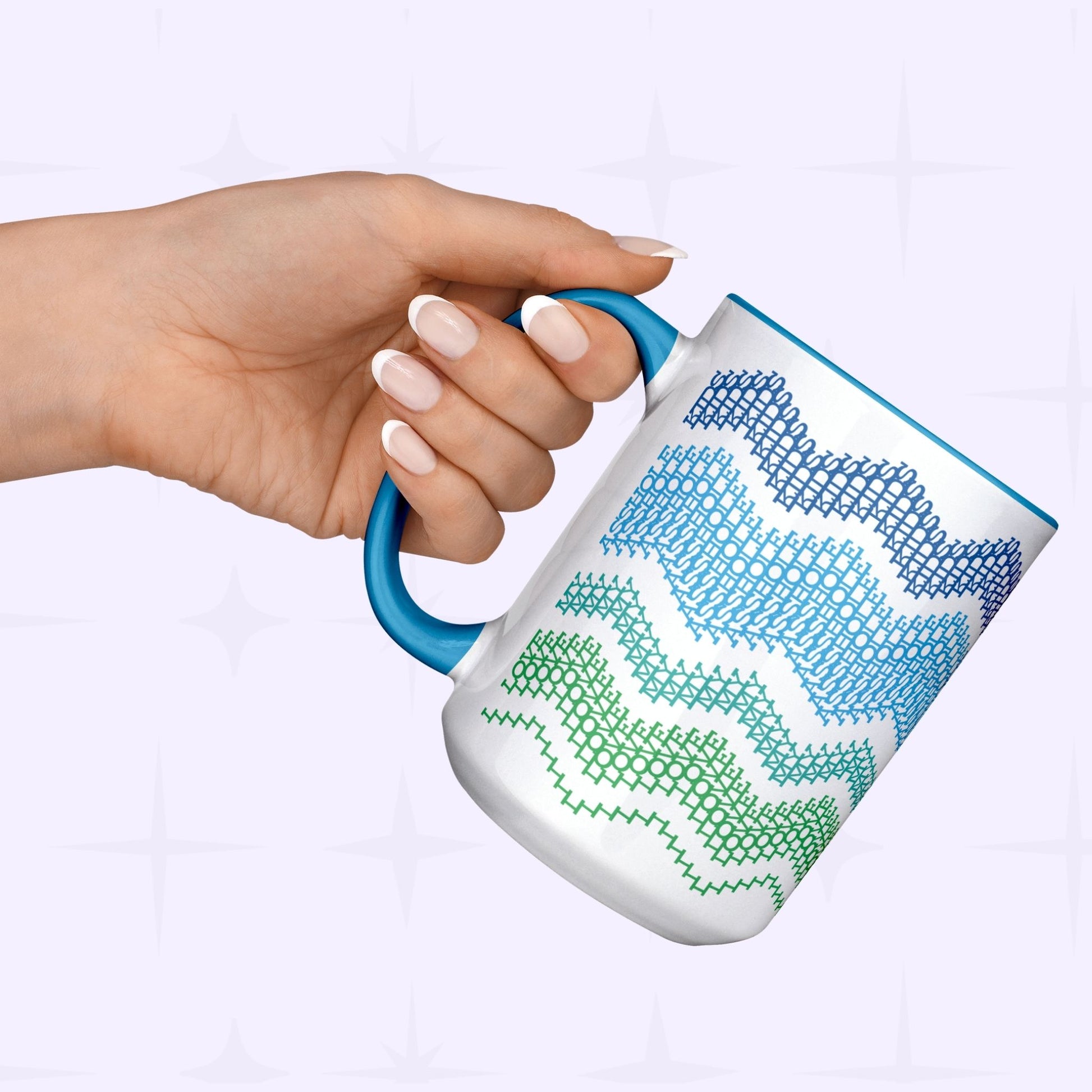 Hand holding Ocean & Blue hidden message mug by its blue handle against a light lavender background — showing the navy-to-green typographic fair isle wave pattern