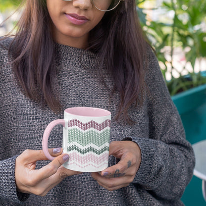 Preppy & Pink hidden message mug 11oz held in both hands outdoors with green plants in background — showing the full burgundy, sage, forest green, and pink typographic pattern