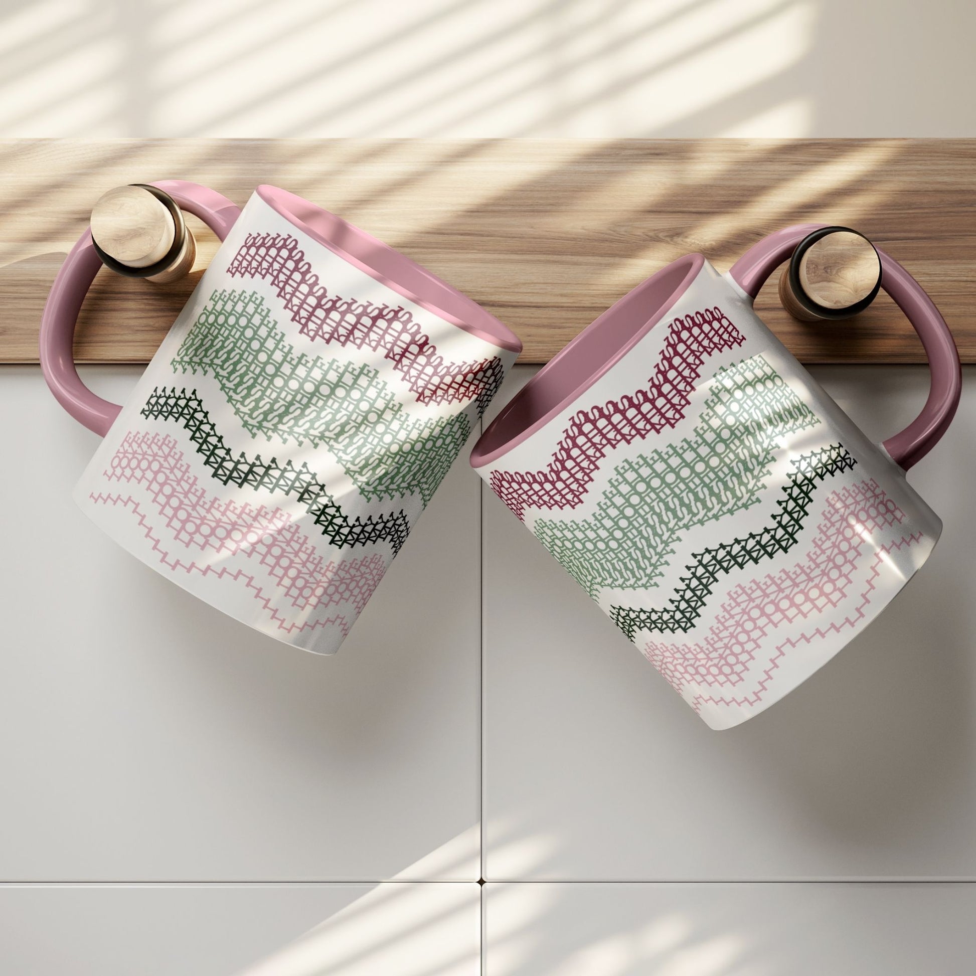 Two Preppy & Pink hidden message mugs resting on a wooden kitchen shelf ledge against white tile — overhead lifestyle shot showing both sides of the typographic pattern