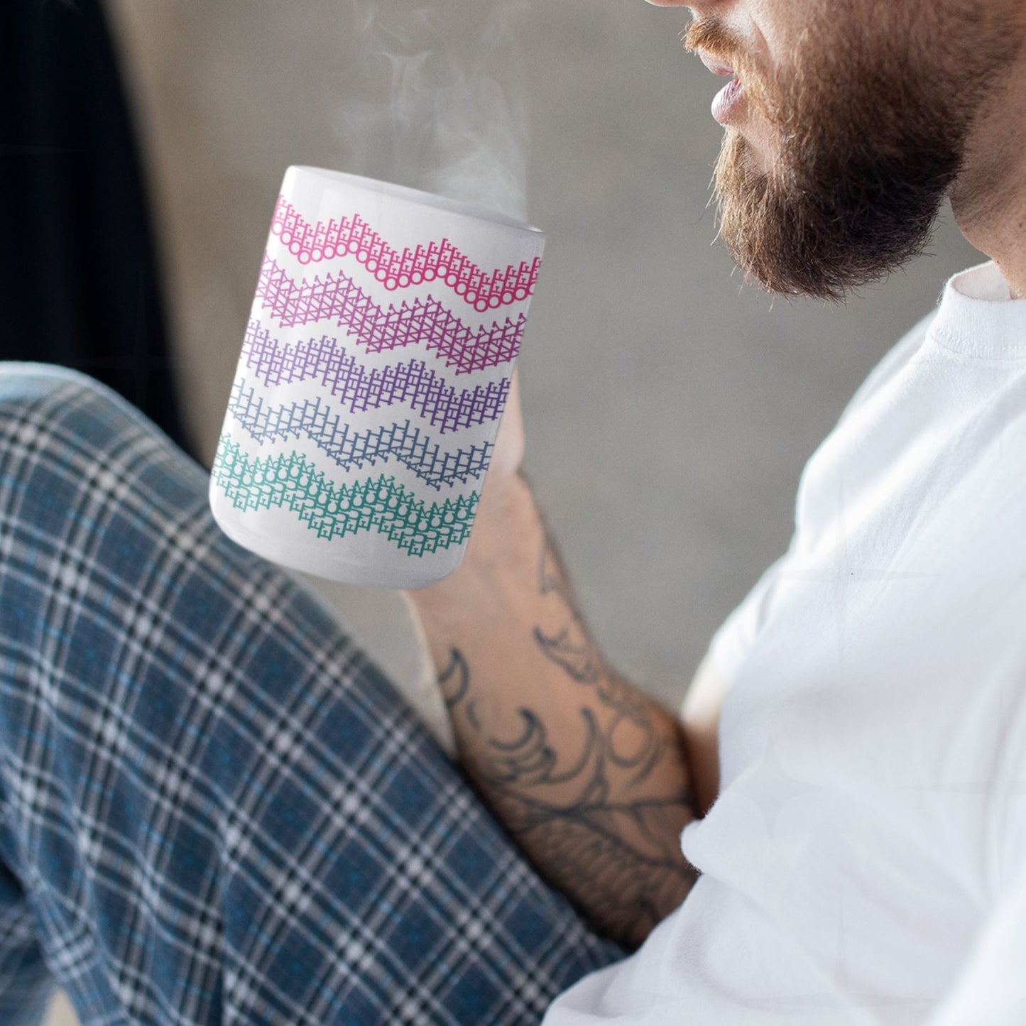Bearded man with arm tattoos drinking from bright stripes hidden profanity chevron mug in hot pink purple and teal, steam rising