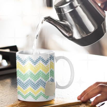 Hidden message cross stitch mug with Go Fuck Yourself text visible in chevron pattern, tea bag inside, hot water being poured from kettle