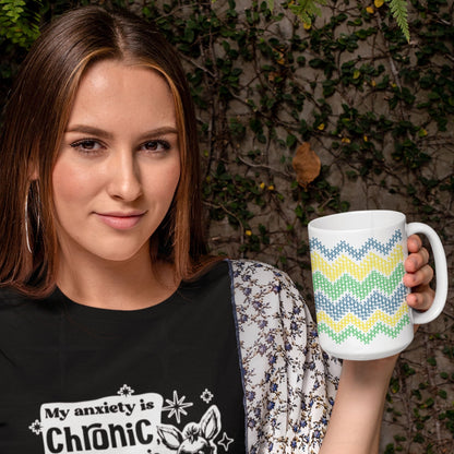 Woman holding hidden message cross stitch coffee mug with bright teal yellow green stripes outdoors against ivy wall