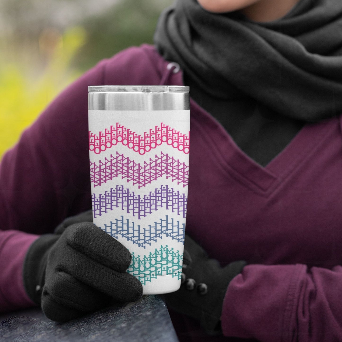 Person in plum hoodie and gloves holding bright stripe hidden profanity tumbler outdoors in cold weather