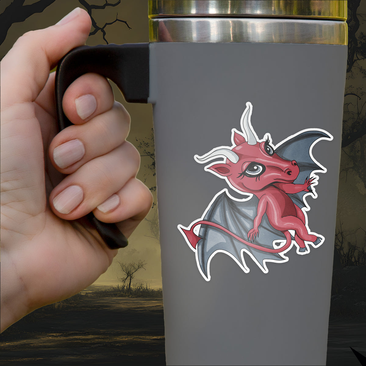 The Jersey Devil sticker, a crimson winged figure with pale horns, applied to a gray travel mug held by hand
