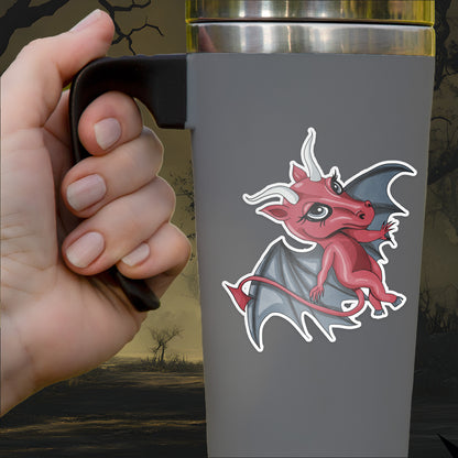 The Jersey Devil sticker, a crimson winged figure with pale horns, applied to a gray travel mug held by hand