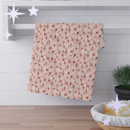 Dusty rose mid century modern tea towel with atomic starburst pattern hanging across white towel rack against white subway tile kitchen wall