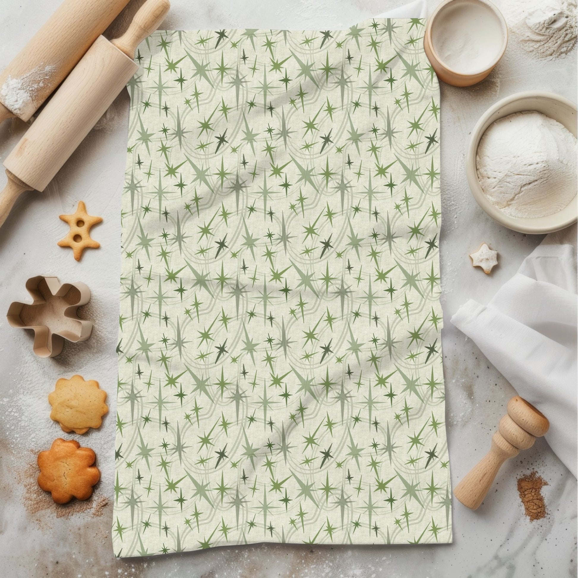 Sage green retro olive tea towel with mid-century portrait repeat pattern, styled flat on marble surface with rolling pin and cookies