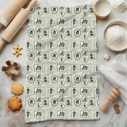 Sage green retro olive tea towel with mid-century portrait repeat pattern, styled flat on marble surface with rolling pin and cookies