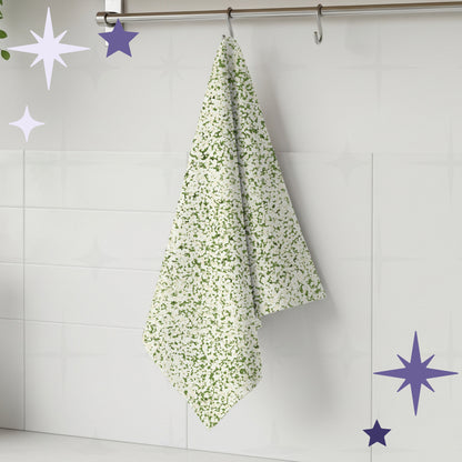 Sage green terrazzo print tea towel hanging from stainless steel rail hook on white tile kitchen wall