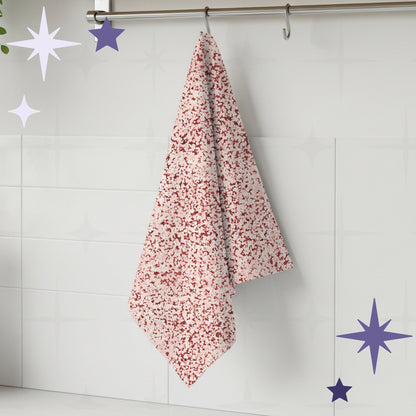 Terracotta red terrazzo print kitchen towel hanging from stainless steel rail hook on white tile kitchen wall