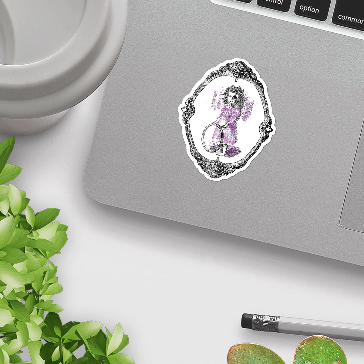 Victorian gothic sticker applied to the corner of a silver laptop beside a mug and plant